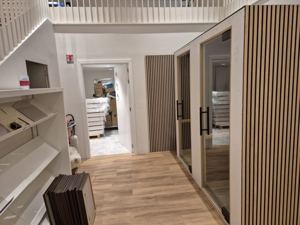 Acoustic booth with timber slat cladding and glass door, installed beside the shelving at the BPI Lumière