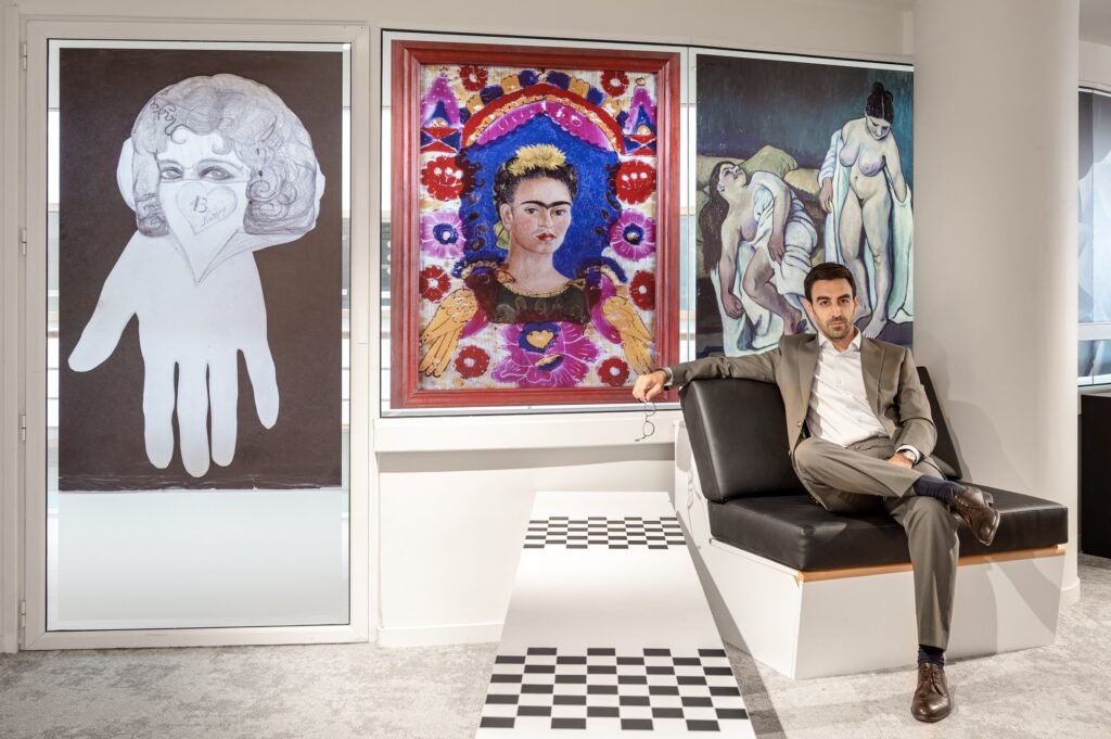 Andrés Mariño Maza sentado en un banco tapizado junto a obras de arte enmarcadas en la BPI Lumière, París