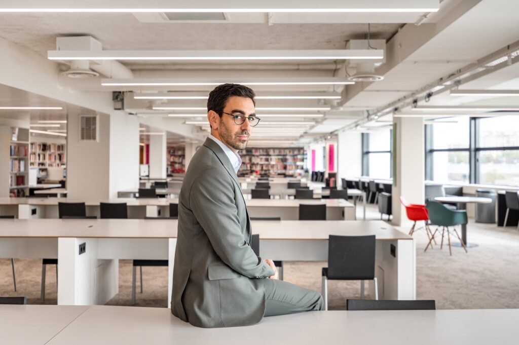Andrés Mariño Maza sentado sobre una mesa de estudio en la sala de lectura de la BPI Lumière, París