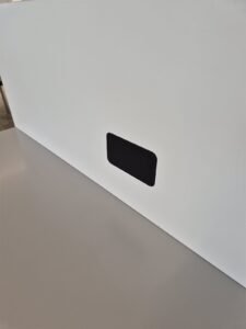 Tapa negra impresa en 3D encajada en un panel blanco.