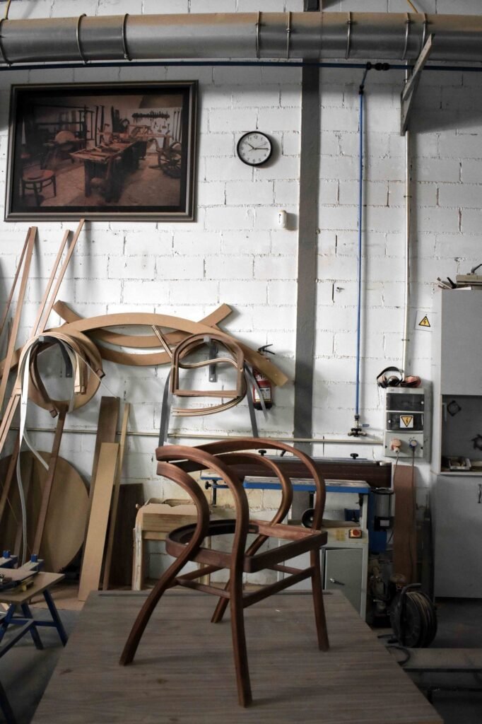 Walnut armchair in progress on a workbench in the Madrid workshop, with steam-bent parts on the wall behind
